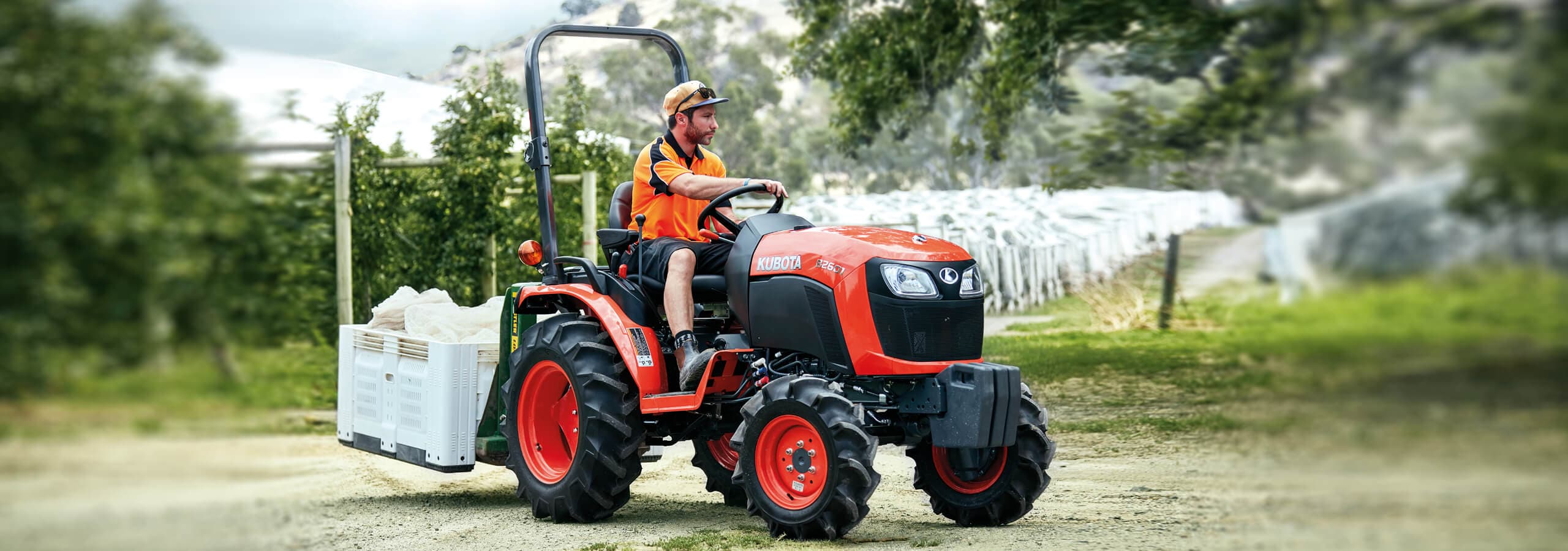 Kubota B01 Series compact tractors working on a rural property